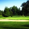A view of a green guarded by a large bunker at Acton Golf Club
